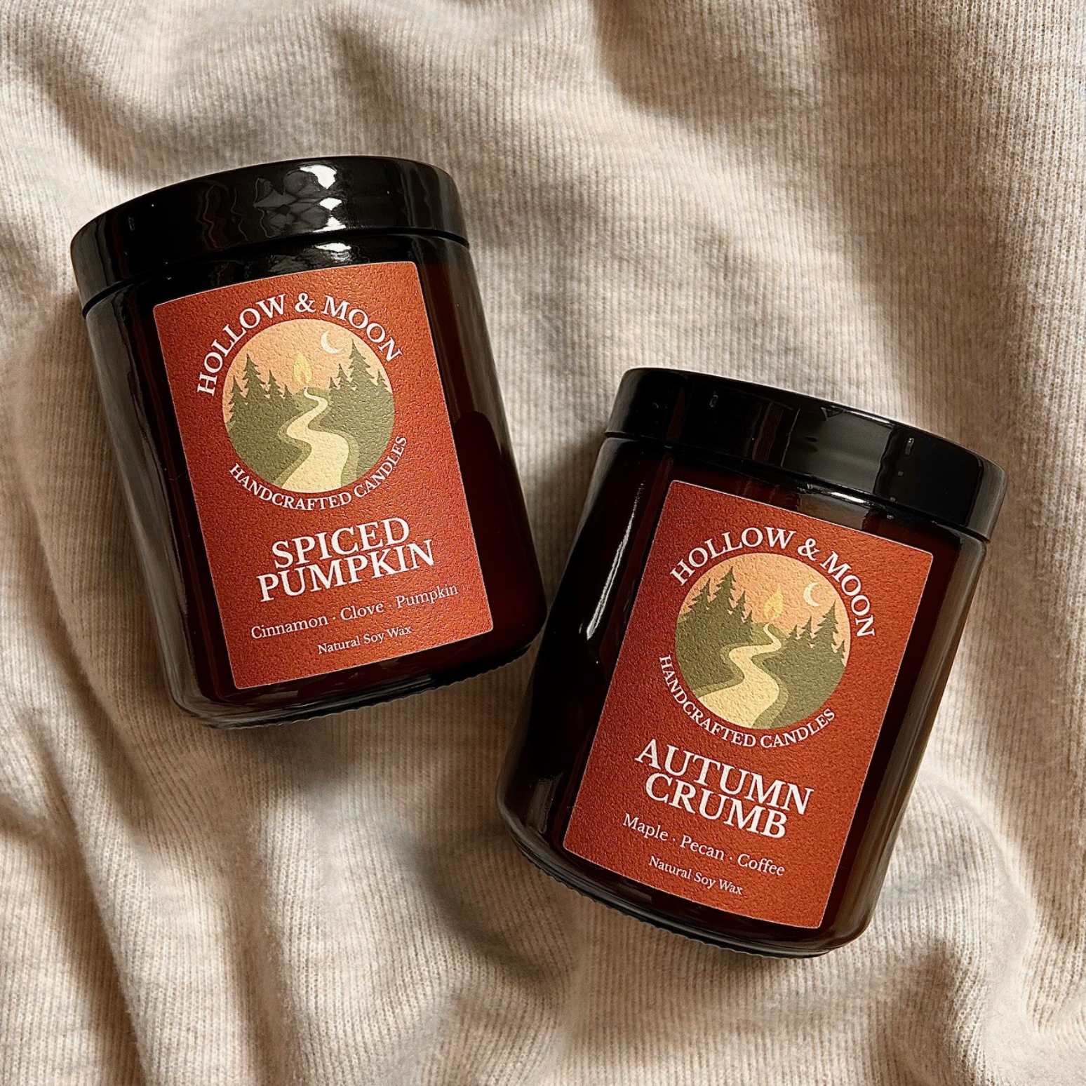 Two candles from Hollow & Moon on a beige fabric background